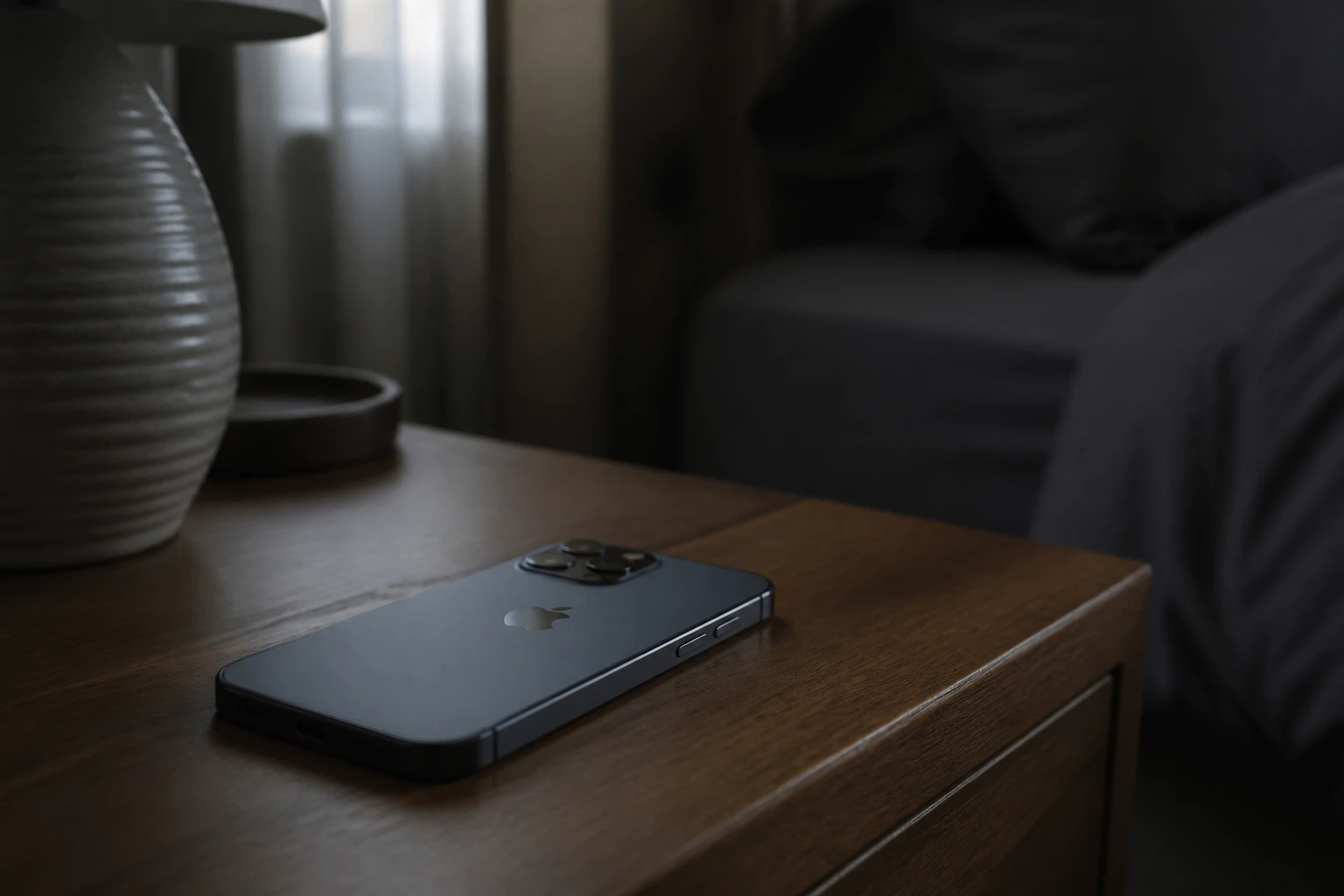 Smartphone posé face vers le bas sur une table de nuit sombre, en mode éteint ou mode avion, lumière douce