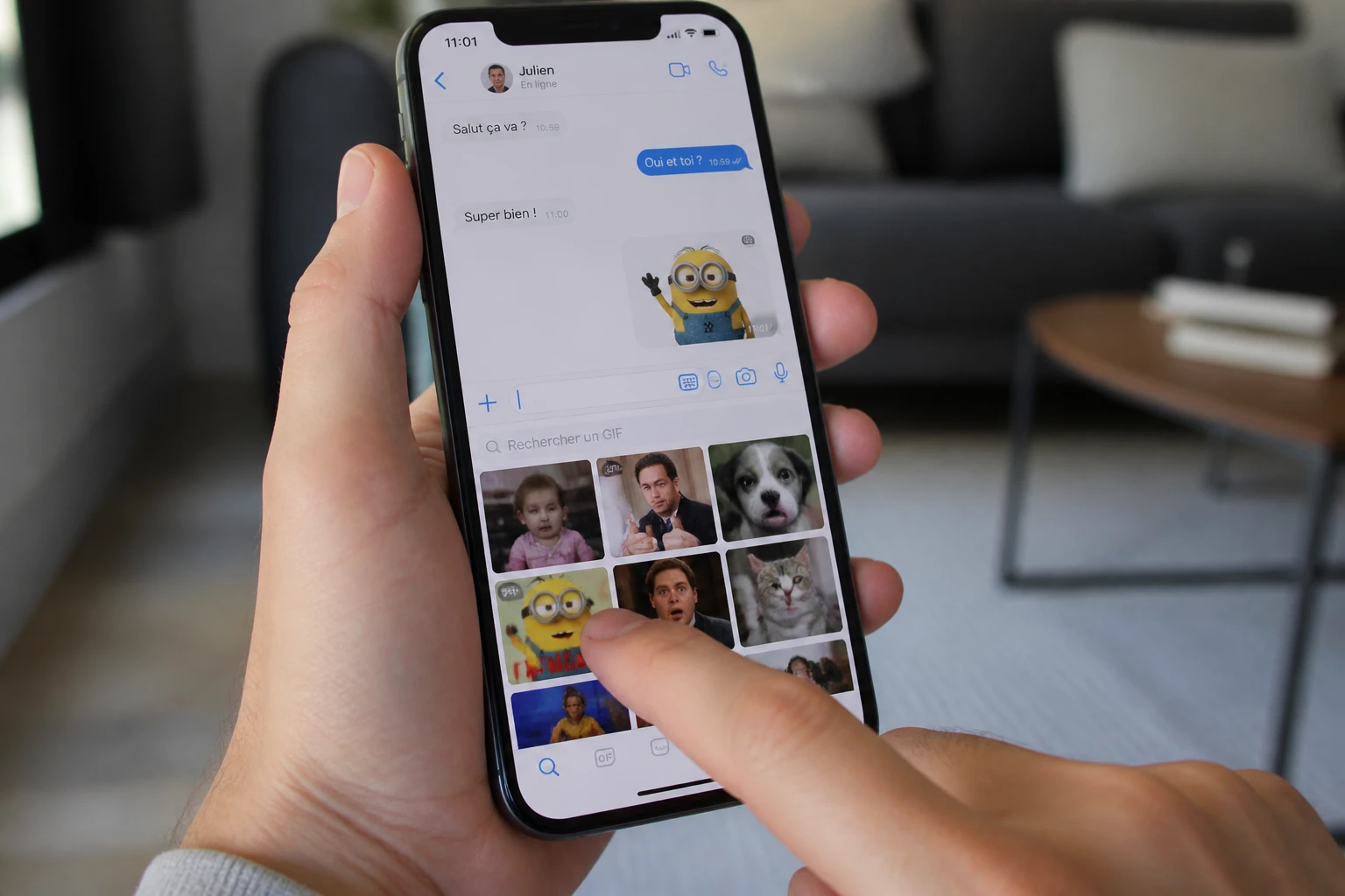 Main tenant un smartphone avec une bibliothèque de GIF animés ouverte dans une conversation de messagerie